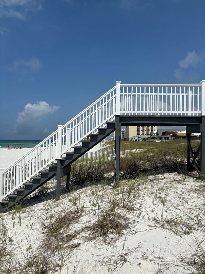 A custom white deck and staircase built leading over the dunes to a Gulf Coast beach