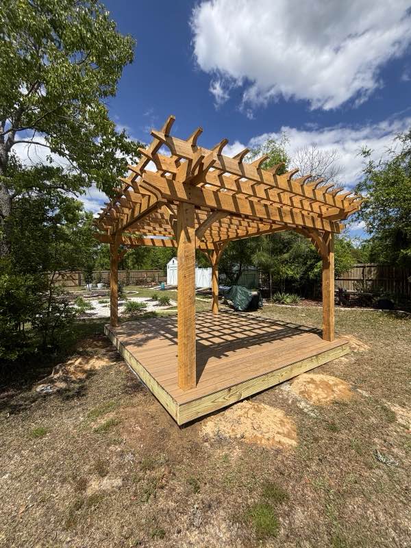 Custom cedar pergola built over a wood deck platform in a backyard
